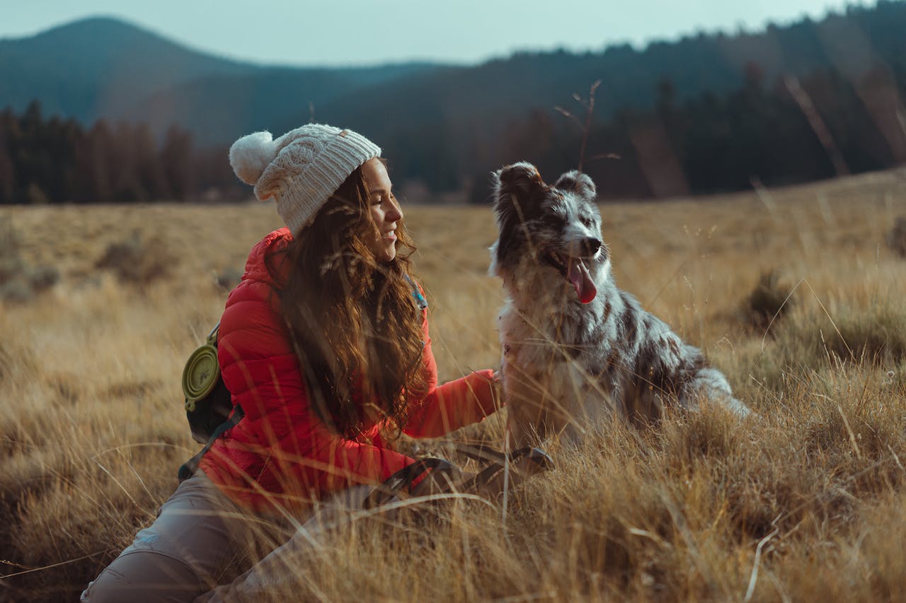 A woman and her dog enjoy a serene outdoor adventure in a grassy field.
